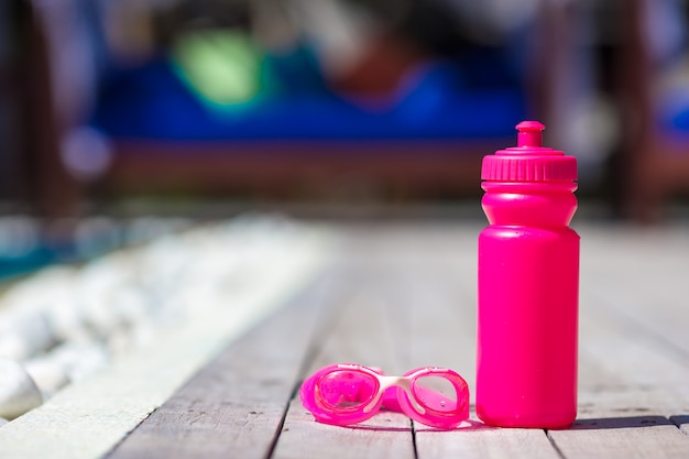 Foto botella de agua deportiva rosa cerca de la piscina