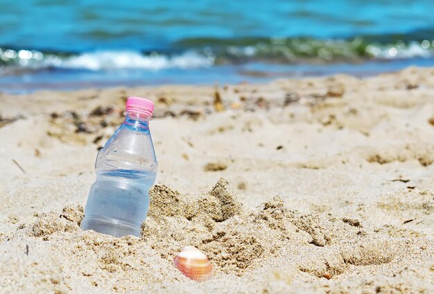 Botella con agua dulce atrapada en la arena.