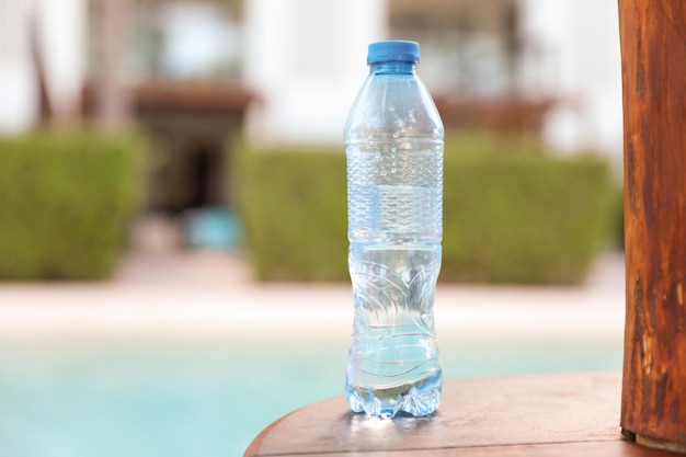 Una botella de agua está sobre una mesa junto a la piscina.