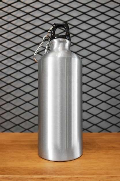 Foto botella de agua y mosquetón metálicos en el fondo de madera del estante.