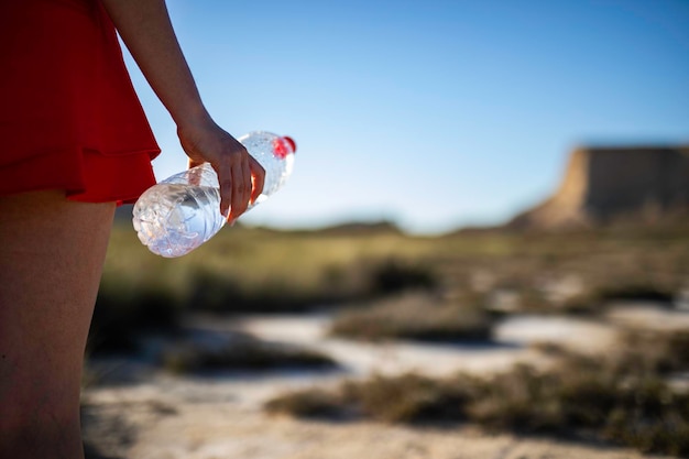 Botella de agua de plástico sin etiqueta en suelo árido en un paisaje desértico con espacio para copiar