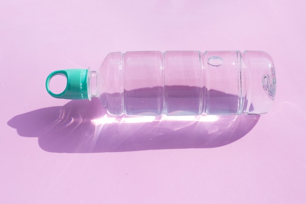 Botella de agua de plástico sobre superficie rosa