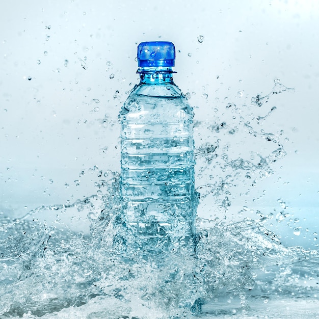 Foto botella de agua salpicada sobre un fondo azul.