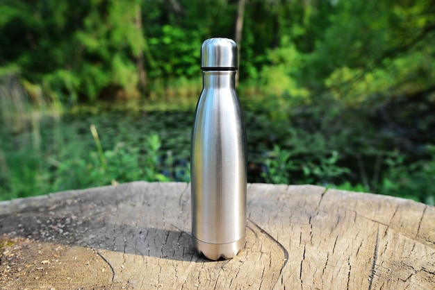 Botella de agua sobre tocón de madera en medio del bosque