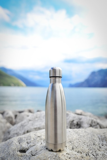 Botella de agua termo eco de acero en el fondo del lago en las montañas