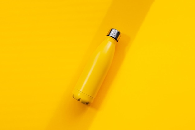 Botella de agua termo de metal de color amarillo sobre fondo amarillo Vista superior de cierre