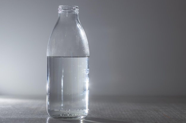 Botella de agua de vidrio sobre un fondo gris. copia espacio