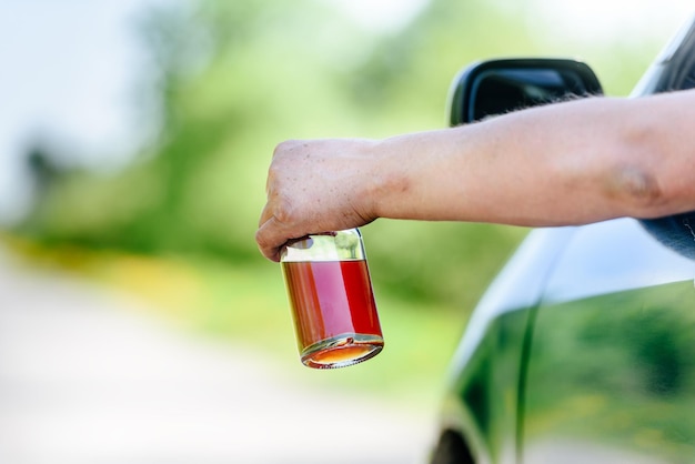 Botella de alcohol y coche el concepto es no beber mientras se conduce Un hombre bebe alcohol al volante