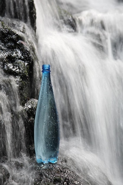 Una botella azul de agua mineral fresca en cascadas