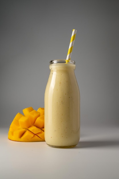 Botella de batido de mango, plátano y yogur con pajita