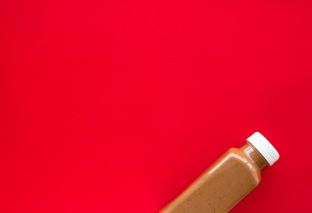 Botella de batido de plátano y chocolate en flatlay rojo