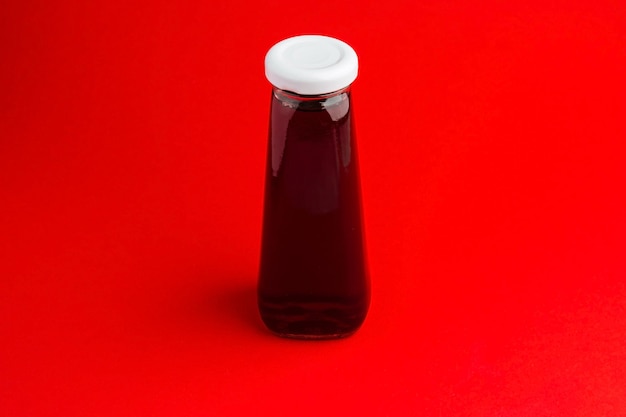 Botella con bebida líquida roja sobre fondo de pimiento rojo Jugo de cereza