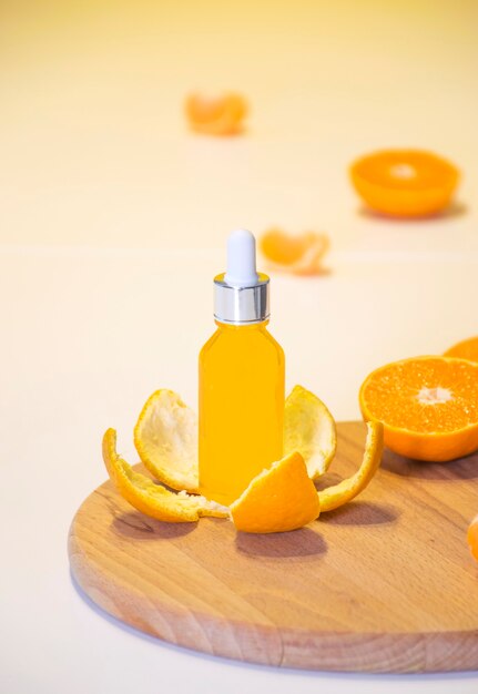 Botella de bio suero orgánico con vitamina C en cáscara de mandarina con trozos de naranja sobre fondo blanco.