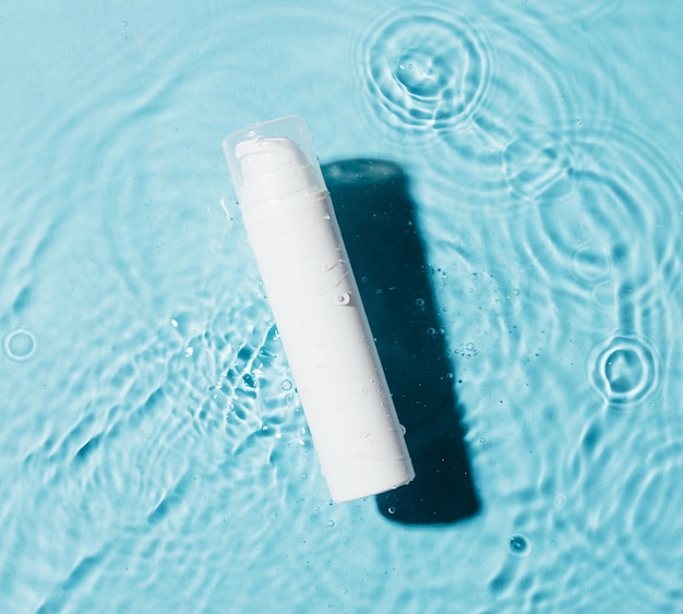 Botella blanca cuidado de la piel spa producto cosmético piscina agua fondo azul Concepto de belleza de moda