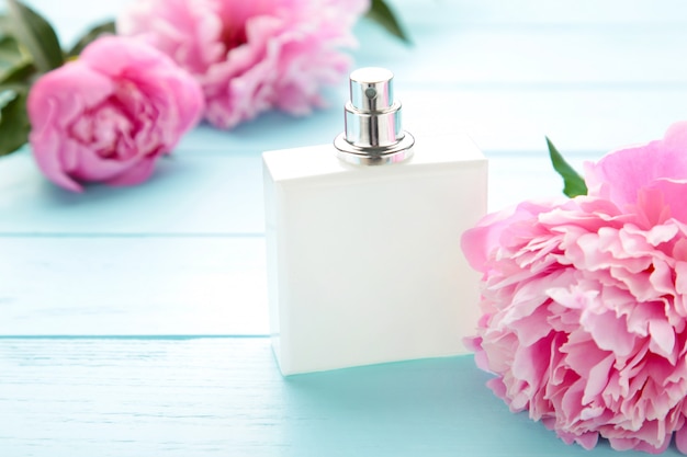 Botella blanca de perfume con flores rosas sobre rosa