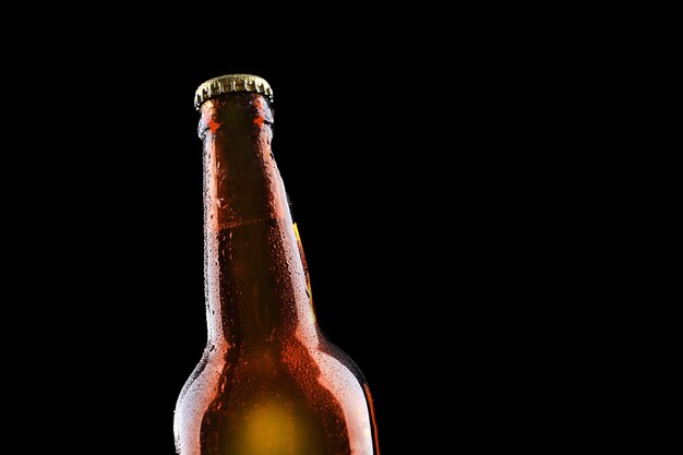 Foto botella de cerveza de cristal sobre fondo negro