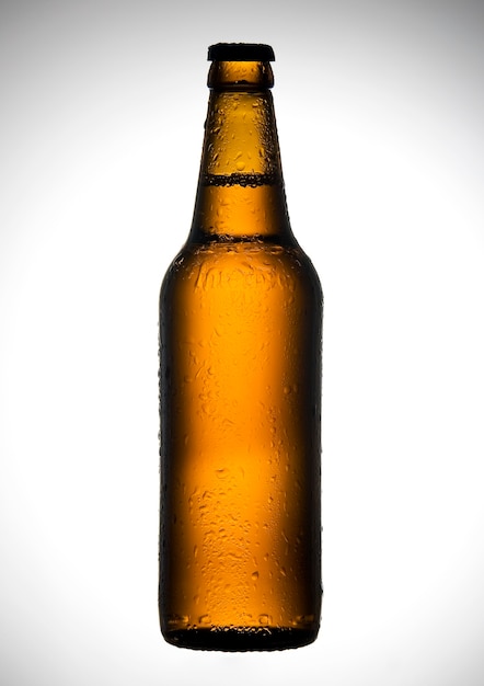 Foto botella de cerveza con gotas en la pared blanca