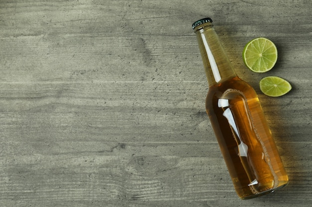 Botella de cerveza y limón sobre fondo de textura gris