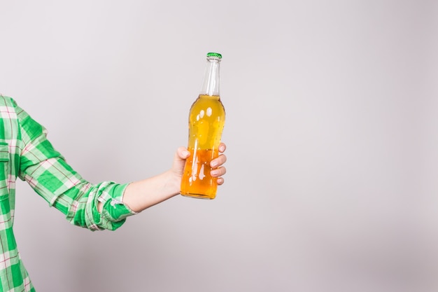 Foto botella de cerveza en la mano sobre fondo blanco.