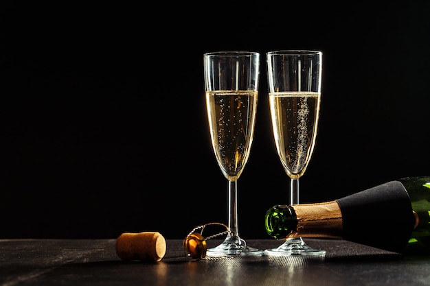 Botella de champagne y copas sobre oscuro