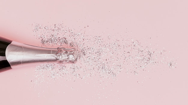 Foto botella de champagne con fondo rosa