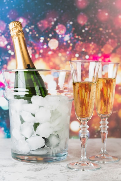 Foto botella de champagne con hielo y vasos.