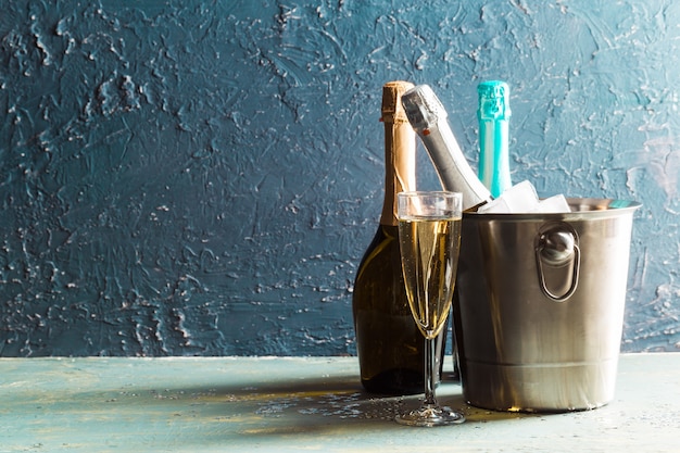 Botella de champán en balde con hielo y copas de champán