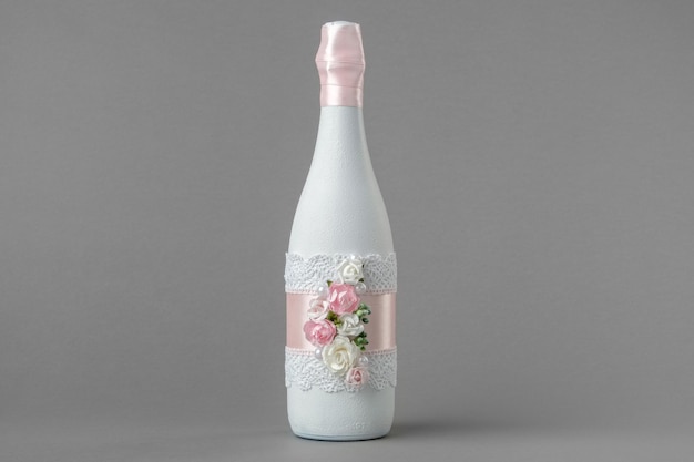 Botella de champán de boda decorada con encaje de rosas y cinta