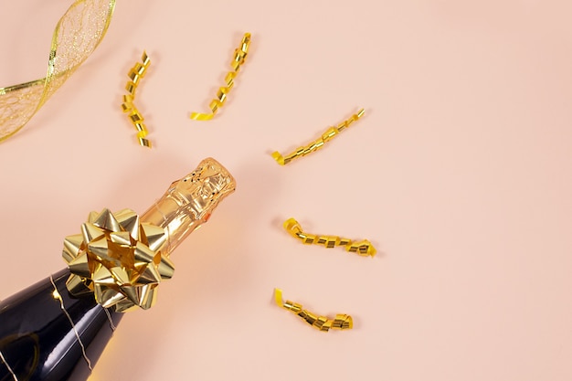 Botella de champán con cintas doradas y confeti. Celebración de fin de año