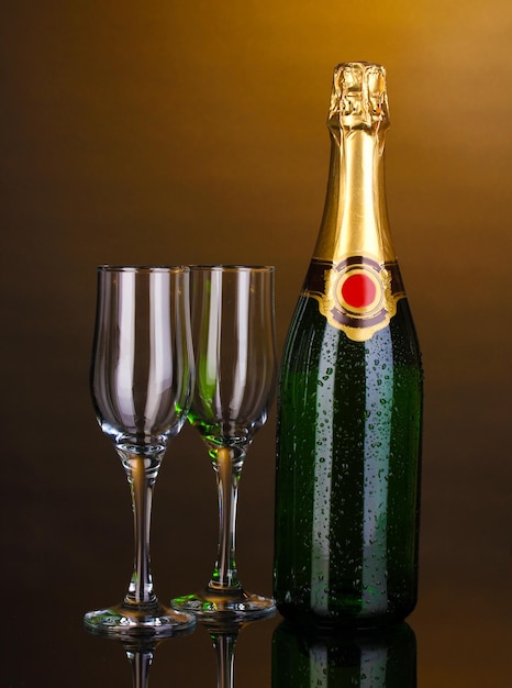 Botella de champán y copas sobre fondo marrón