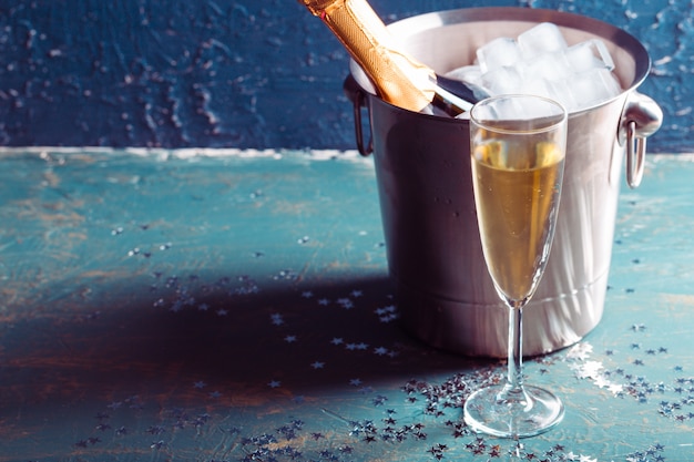 Botella de champán en un cubo con hielo y copas de champán