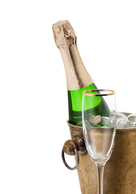 Botella de champán en enfriador y copa de champán