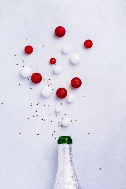 Botella de champán de Navidad con chispitas de color blanco sobre blanco.