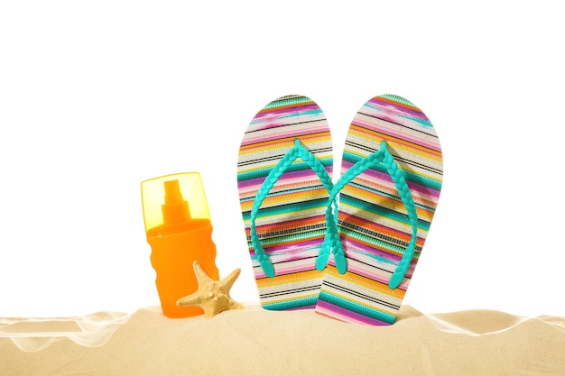 Botella de chanclas con crema y estrellas de mar sobre arena contra fondo blanco Concepto de vacaciones de verano