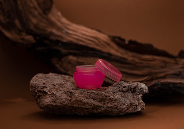 La botella de color rosa crema se encuentra sobre una piedra clara con un fondo de madera. Concepto natural. Botella de ÃƒÂƒÃ‚Â ÃƒÂ‚Ã‚Â¡ream rosa sobre un fondo natural.