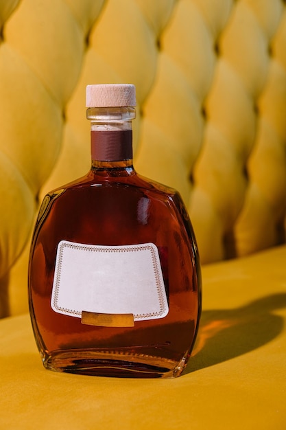 botella de coñac o brandy de élite sobre un fondo de textura amarilla