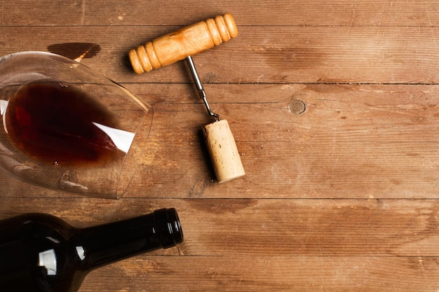 Una botella y una copa de vino con un viejo sacacorchos sobre una mesa de madera