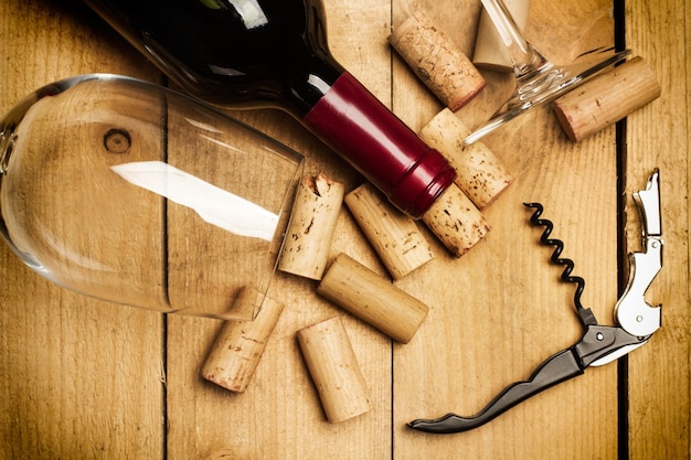 Una botella de copas de vino y corchos en una mesa de madera rústica en una vista superior