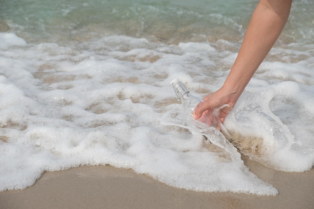 Foto botella cortada con un mensaje en la playa