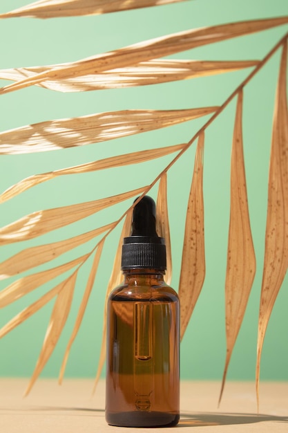 Botella cosmética con aceite corporal y facial en hoja de palma verano cosmética natural suero aceite facial concepto tropical