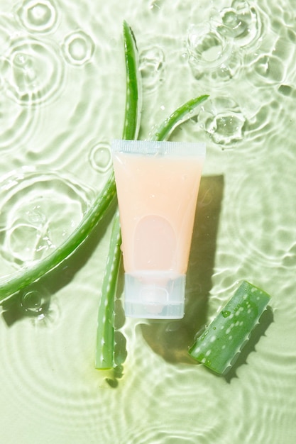 Botella cosmética con aloe en agua.