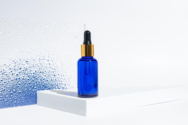 botella cosmética de vidrio azul con un gotero sobre un fondo blanco con gradiente azul concepto de cosméticos naturales aceites esenciales naturales y productos para el cuidado de la piel