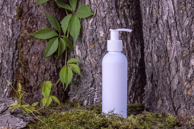 Una botella de cosméticos en el fondo de la corteza de los árboles y las hojas verdescosméticos naturales