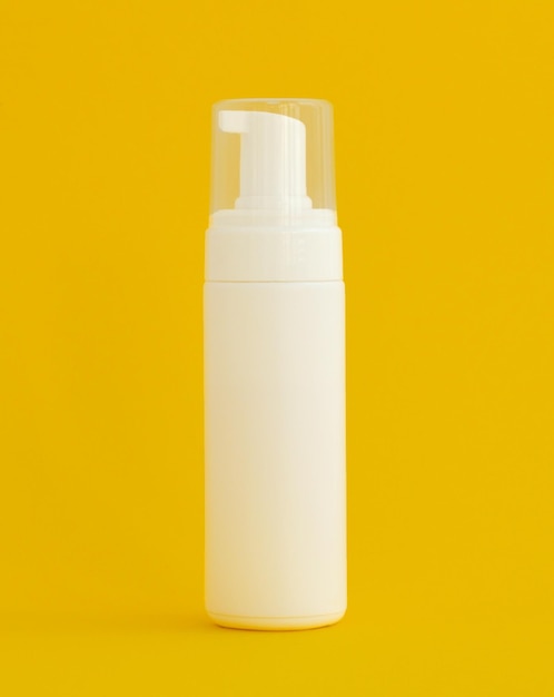 Botella de crema hidratante cosmética Botella de cosméticos de plástico en blanco sobre fondo amarillo con espacio de copia