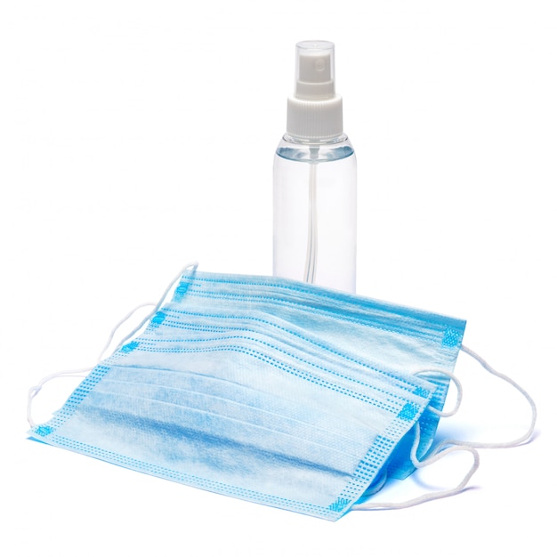 Botella de crema, loción, desinfectante o jabón líquido y máscara protectora sobre mesa blanca