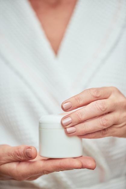 Botella de crema en manos de mujer cuidadas