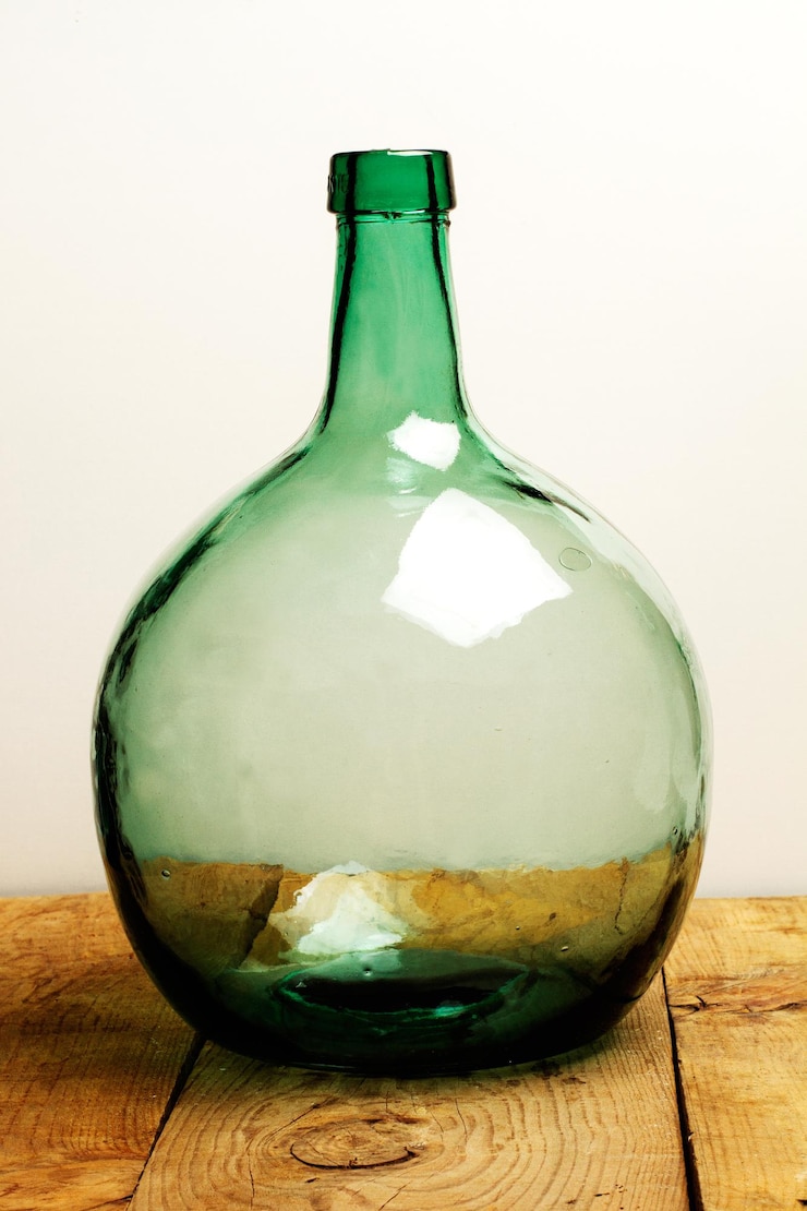 Botella de cristal grande vintage sobre una mesa de madera