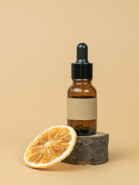 Una botella con un cuentagotas sobre un árbol viejo y una naranja seca sobre un fondo beige Cosméticos y medicamentos a base de minerales naturales
