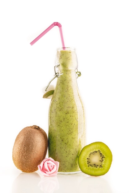 Foto botella de delicioso batido de kiwi verde con rodajas de kiwi y una pequeña flor aislada sobre fondo blanco. concepto de comida sana, detox y dietética.