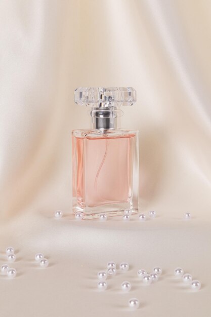 Botella elegante de perfume para mujeres con fragancias delicadas en un fondo de satén beige con perlas Fondo vertical Presentación